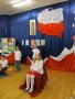 Dziewczynka, odgrywająca Polskę na tle dekoracji składającej się z symboli narodowych.