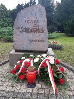 Kwiaty i pamiątkowy znicz pod obeliskiem na Skwerze Solidarności.