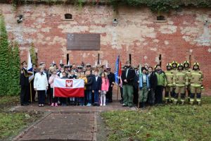 Grupa uczestników uroczystości pod tablicą upamiętniającą I port marynarki wojennej.