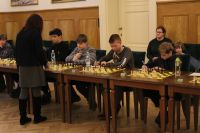 Kilku chłopców siedzących przy stołach z szachami na...