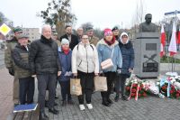 Grupa kobiet i mężczyzn przy pomniku z popiersiem mężczyzny.