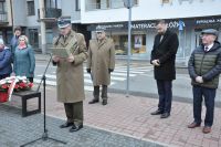 Mężczyzna w mundurze mówi do mikrofonu trzymając w rękach teczkę na dokumenty.
