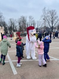 Osoba w stroju niedźwiedzia, w długiej czapce bawi się z sześciorgiem dzieci.