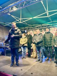 Za mężczyzną na scenie stoją trzy kobiety i trzech mężczyzn.