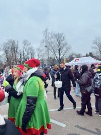 Kilkanaście osób wokół mężczyzny idącego z koszykiem.