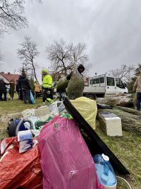 Za elektrośmieciami kilka osób trzyma choinki owinięte w siatki.