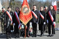 Cztery dziewczęta i dwóch chłopców w szarfach biało-czerwonych stoją ze sztandarem szkoły.
