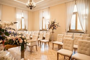 Kilkadziesiąt tapicerowanych białych krzeseł na drewnianych, brązowych nogach.