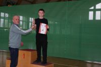 Mężczyzna wręcza puchar chłopcu stojącemu na podium.