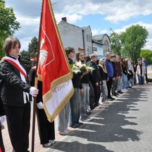 Nastolatek trzyma prawą ręką drzewiec ze sztandarem.