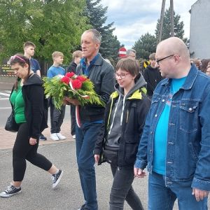 Dziewczyna, chłopak i dwóch mężczyzn idących obok siebie. Jeden z mężczyzn trzyma w rękach wiązankę kwiatów.