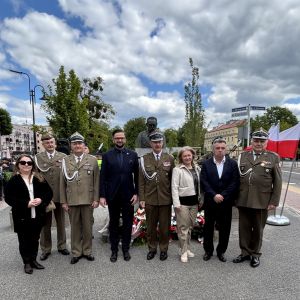 Dwie kobiety, dwóch mężczyzn w garniturach i czterech mężczyzn w mundurach wojskowych.