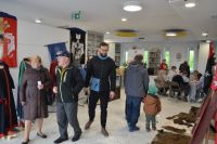 Grupa ludzi w sali z zabytkowymi strojami i oprawionymi skórami zwierząt.