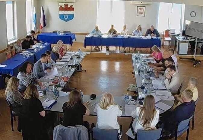 Kobiety i mężczyźni siedzący przy stole w kształcie podkowy.