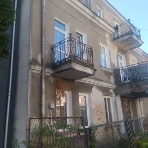 Budynek mieszkalny z dwoma balkonami na pierwszym piętrz i jednym balkonem na drugim piętrze.