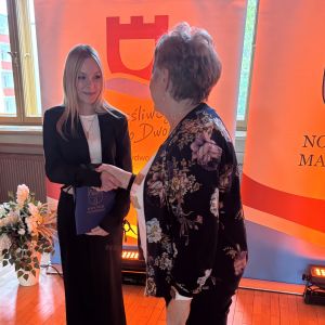 Dziewczyna i kobieta ściskają sobie prawe dłonie.