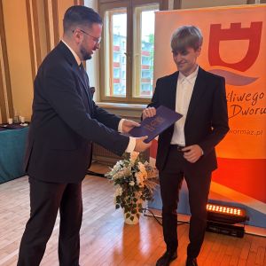Mężczyzna wręcza teczkę chłopcu.