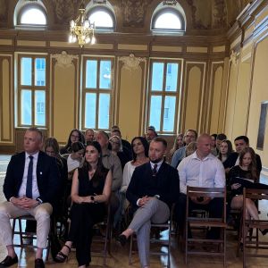 Kobiety i mężczyźni siedzący na krzesłach w dużej sali.