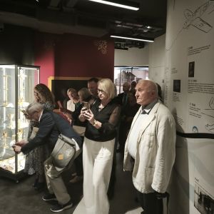 Kobiety i mężczyźni przy szklanej gablocie z przedmiotami liturgicznymi.