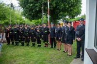 Kilkudziesięcioosobowa grupa młodzieży, kobiet i mężczyzn w mundurach wyjściowych Ochotniczej Straży Pożarnej.