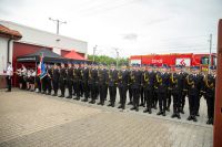 Orkiestra strażacka i kilkudziesięciu mężczyzn w mundurach wyjściowych Państwowej Straży Pożarnej.