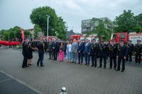 Dwie kobiety w sukienkach, pięciu mężczyzn w garniturach, czterech mężczyzn w mundurach strażackich.
