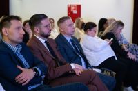 Trzech mężczyzn i kilka kobiet siedzących na krzesłach.