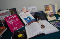 Kilka książek z różnokolorowymi okładkami. Jedna z książek jest otwarta.