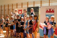 Trzynaście dziewczynek z medalami na szyjach z dyplomami i nagrodami w rękach, w trzy na podium także z pucharami.