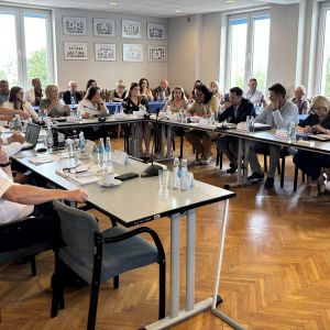 Kilkadziesiąt kobiet i mężczyzn siedzących przy stołach.