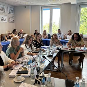 Dziesięć kobiet i trzech mężczyzn siedzących przy stołach.