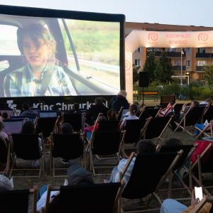 Kilkadziesiąt osób w leżakach plażowych ogląda film wyświetlany na pompowanym ekranie.