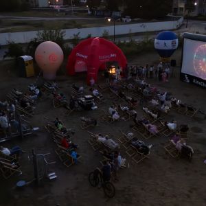 Kilkadziesiąt osób w leżakach plażowych ogląda film wyświetlany na pompowanym ekranie.