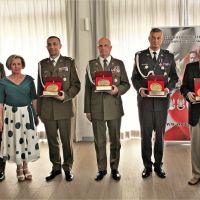 Kobieta, pięciu mężczyzn w mundurach wojskowych i dwóch w garniturach stojących obok siebie.