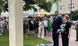 burmistrz i przewodnicząca rady stoją przed pomnikiem, w tle zebrani mieszkańcy