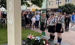 harcerze oddają hołd przed pomnikiem, w tle zebrani mieszkańcy