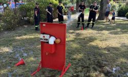 park, grupa młodych strażaków z wężem strażackim leje wodę do celu