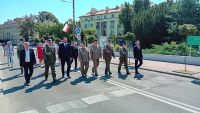 Mężczyźni w mundurach i garniturach idą ulicą.