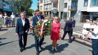 Mężczyzna z wiązanką kwiatów obok niego kobieta i mężczyzna.