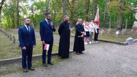 Młodzież ze sztandarem, dwóch mężczyzn w garniturach, dwóch mężczyzn w sutannach.