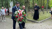 Mężczyzna z wiązanką kwiatów, obok niego mężczyzna w sutannie.