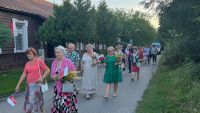 Grupa kobiet niosących w rękach kwiaty i chorągiewki biało-czerwone.