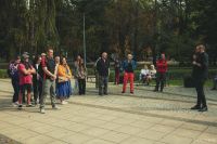 Mężczyzna stojący przed grupą kilkunastu osób, mówiący do mikrofonu.