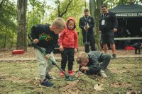Trzech chłopców: jeden z nich trzyma detektor, inny pochyla się nad siatka maskującą.