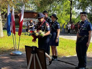 cztery kobiety w mundurach składają kwiaty pod tablicą