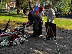 ksiądz z młodzieżą składa kwiaty