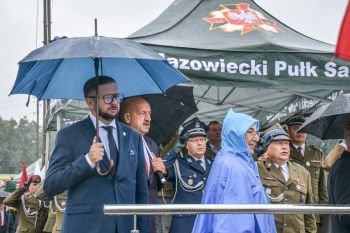 osoby stojące pod namiotem, pada deszcz, na pierwszym planie burmistrz pod parasolem