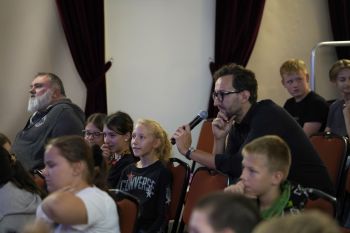 dzieci na sali kinowej w NOK-u, dorośli opowiadają o instrumentach