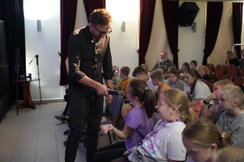 dzieci na sali kinowej w NOK-u, dorośli opowiadają o instrumentach