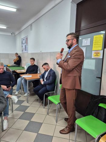 sala, osoby siedzące na krzesełkach, burmistrz trzyma mikrofon